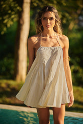 Model relaxing by the pool in a nude Lonarc beachwear dress